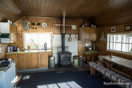 Intérieur du refuge Losjehytta avec le poêle à bois et la grande table